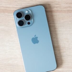 Close-up of a modern smartphone on a light wooden table surface.