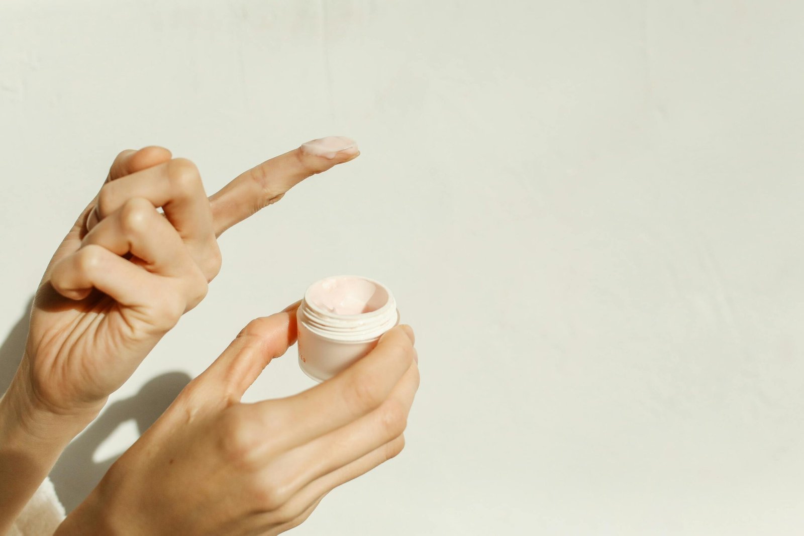 A close-up image showing hands applying facial cream, reflecting a minimalist skincare routine.