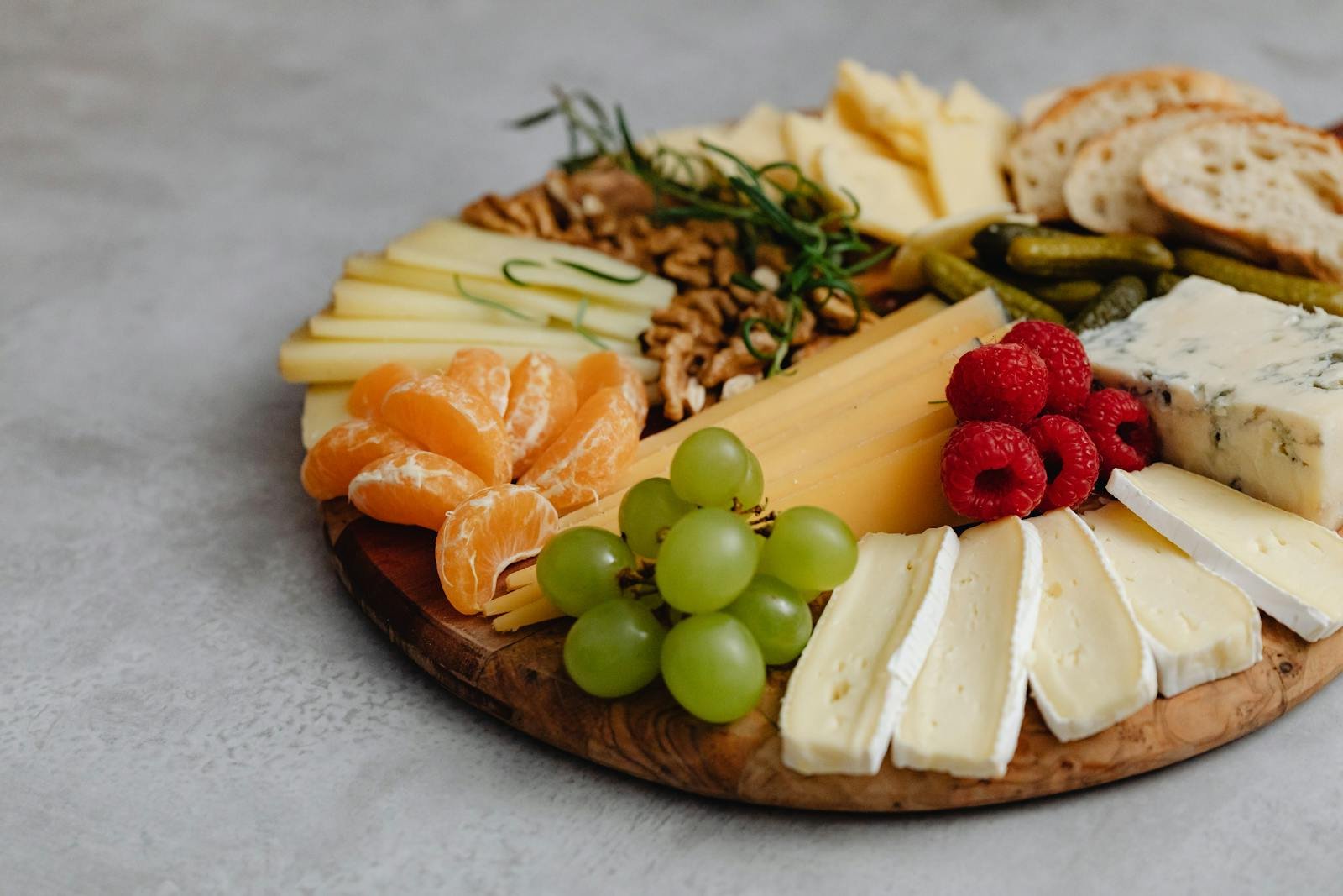 A visually appealing cheese platter with an assortment of fruits, nuts, and crackers.